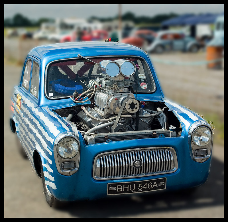 Une voiture bleue avec un énorme moteur qui dépasse de l&rsquo;avant de la voiture en hauteur