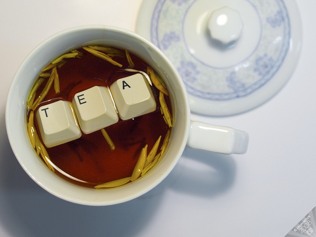 Image d&rsquo;une tasse de thé ayant 3 touches de claviers qui flottent et dont les caractères sont T, E et A